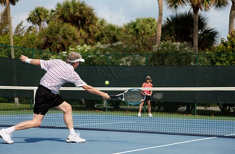Two people playing tennis on outdoor court. Two people playing tennis on outdoor court.