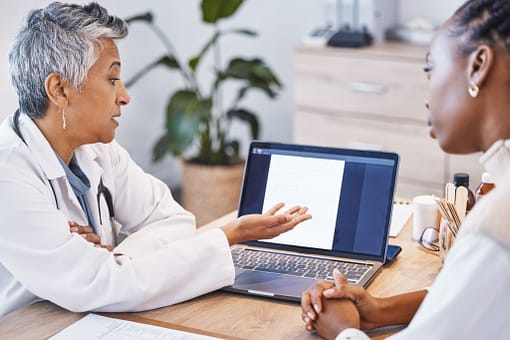 Doctor explaining medical information to a patient using a laptop.